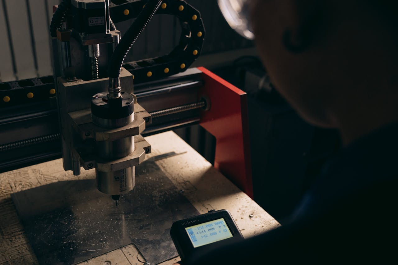 The Art of Drawing Readers In: Your attractive post title goes here A detailed view of a CNC machine being operated by a person indoors with dim lighting.