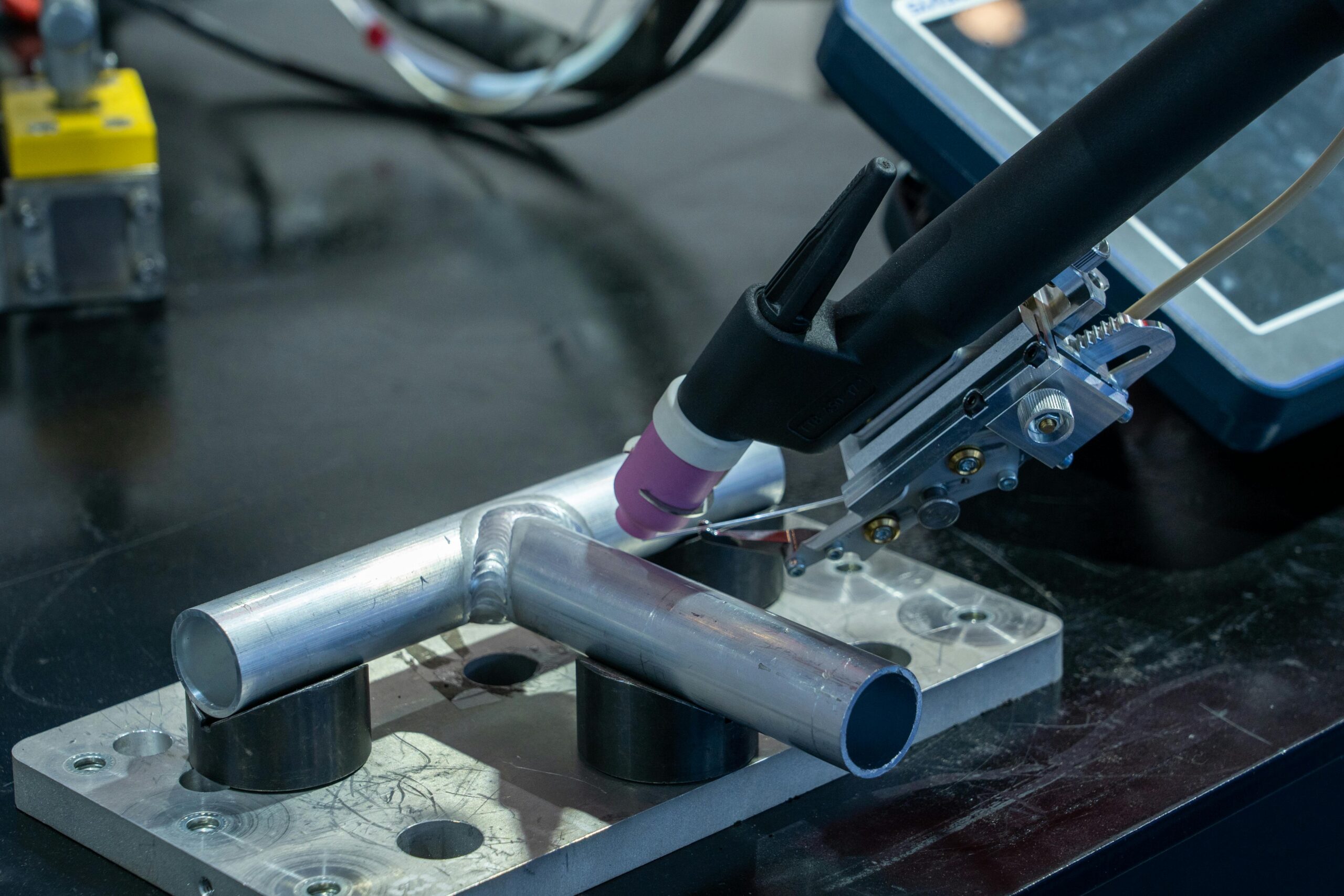 Detailed view of metal welding apparatus in action on industrial workbench.