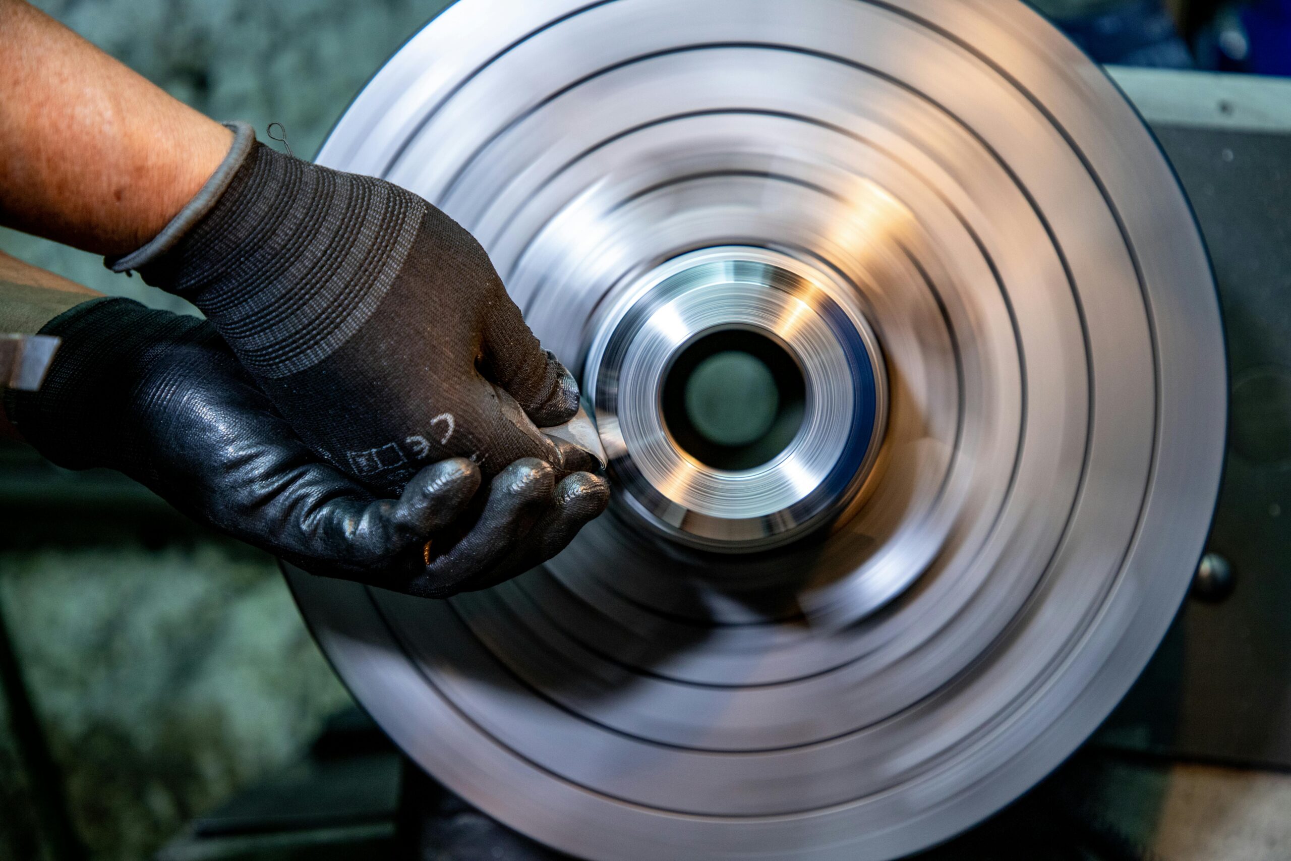 A skilled worker uses precision tools for metal grinding, showcasing craftsmanship in an industrial setting.